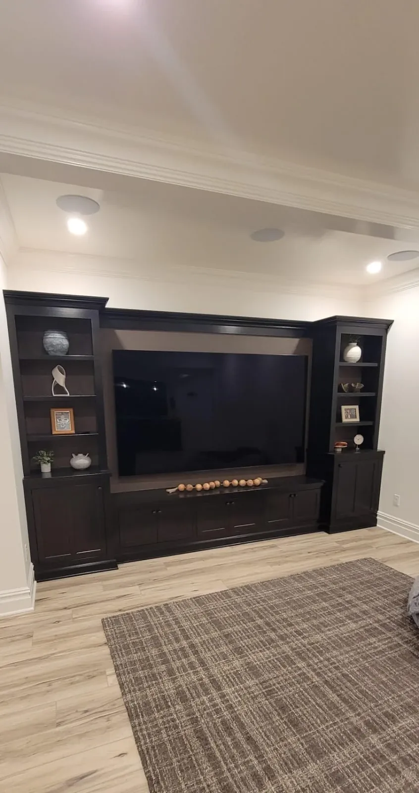 After: custom entertainment center finished in dark espresso with shelves and a mounted TV