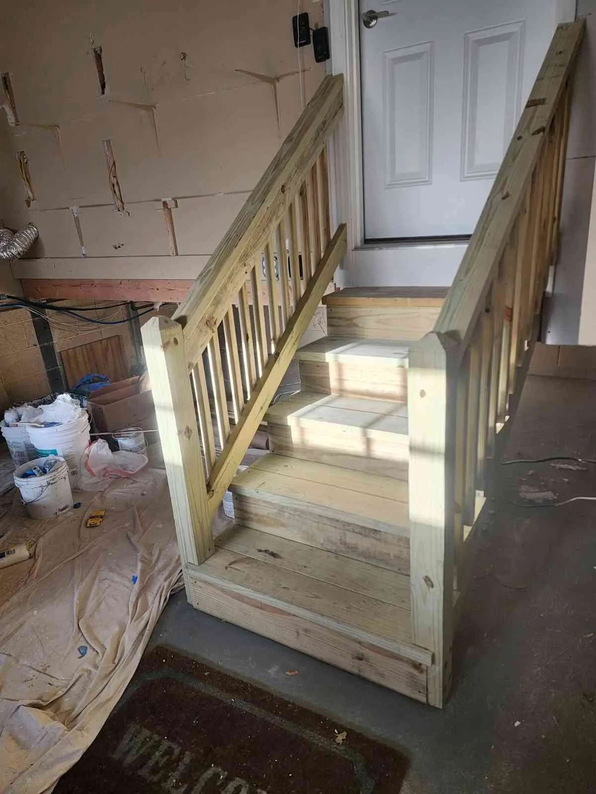Before: unfinished wooden basement stairs with raw lumber railing