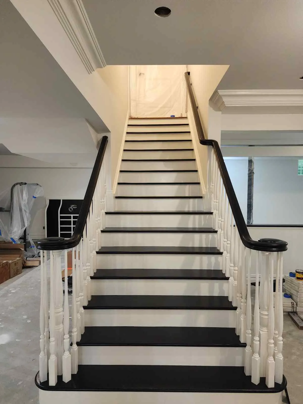 Staircase finished with black treads, white risers, and white balusters